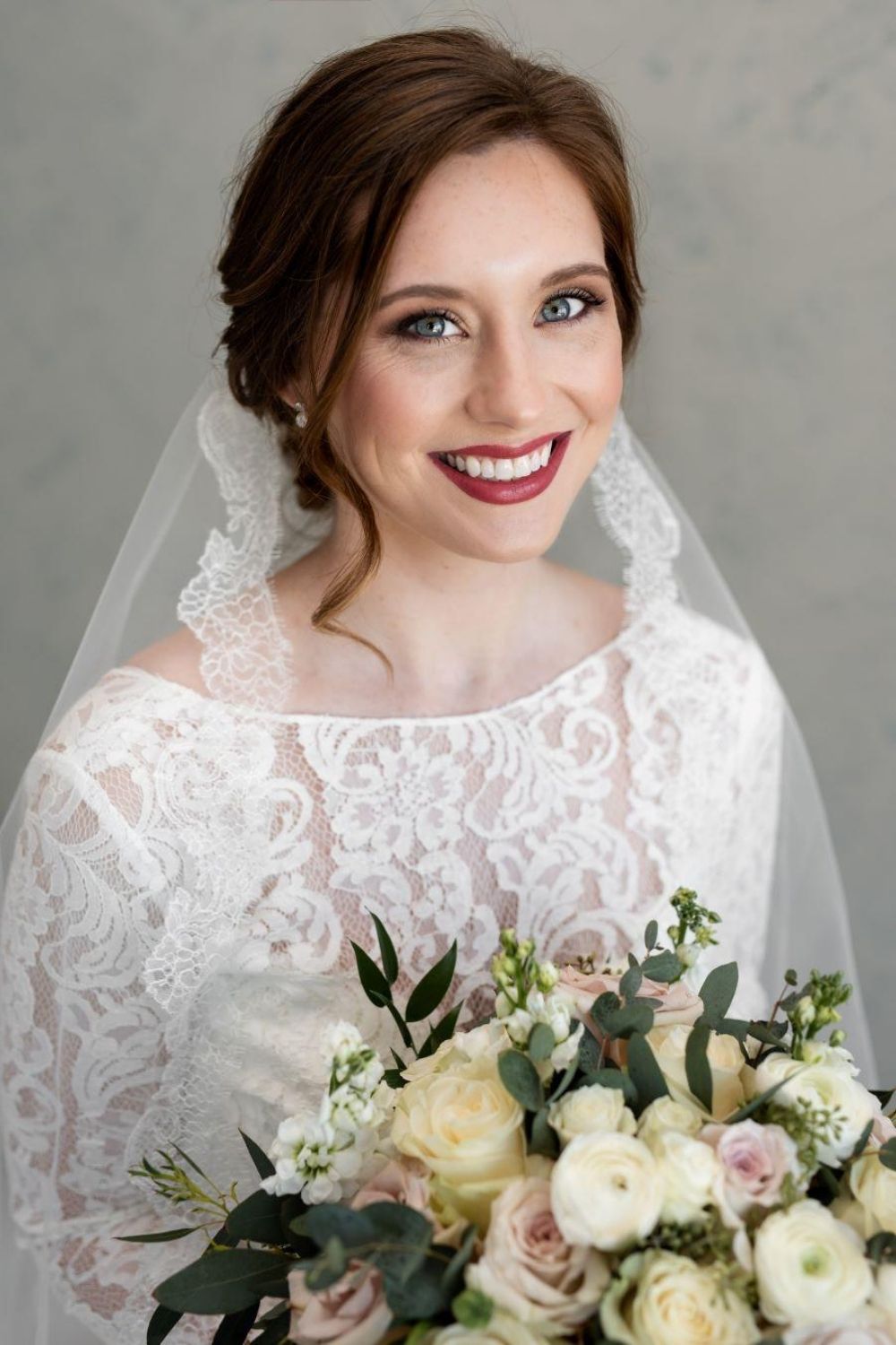 Bride with hair pinned up hairstyle in glam makeup with red lip color