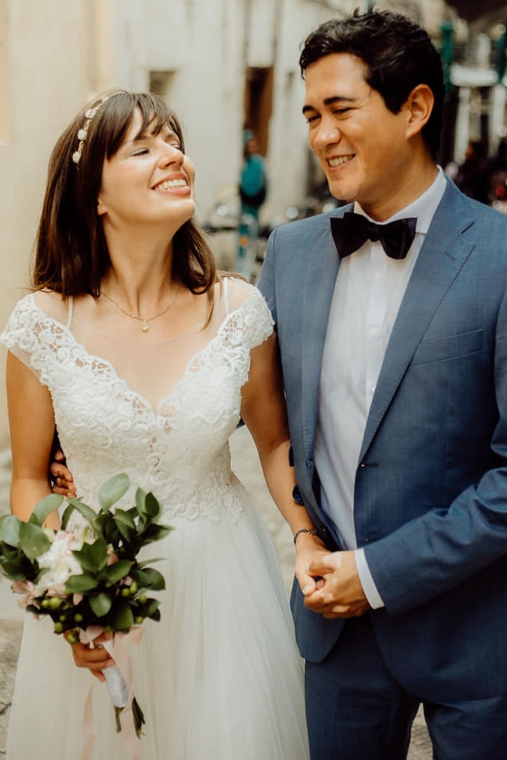 Bride in an off white wedding dress and groom in a blue suit holding hands photo by Green Wedding films