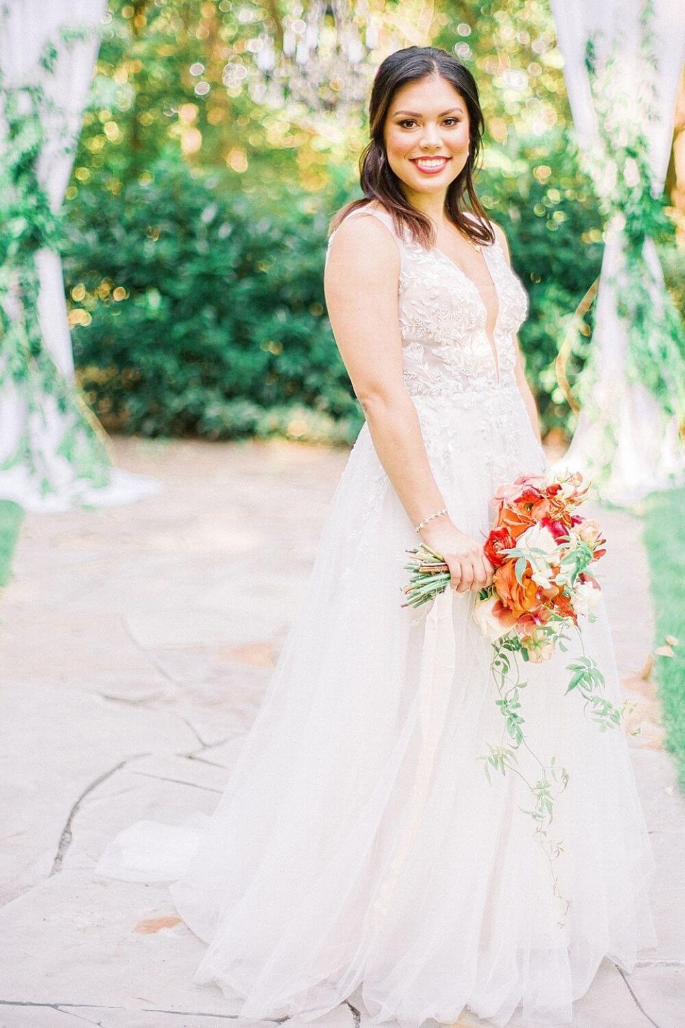 Bride holding orange bouquet in an A-line Wedding Dress photo by Heirloom Rose Photography