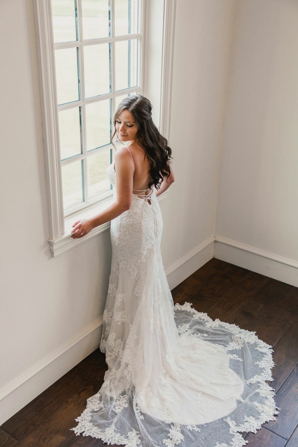 Bride standing at window in a Trumpet-Mermaid Wedding Dress photo by Cortnie Dee Photography