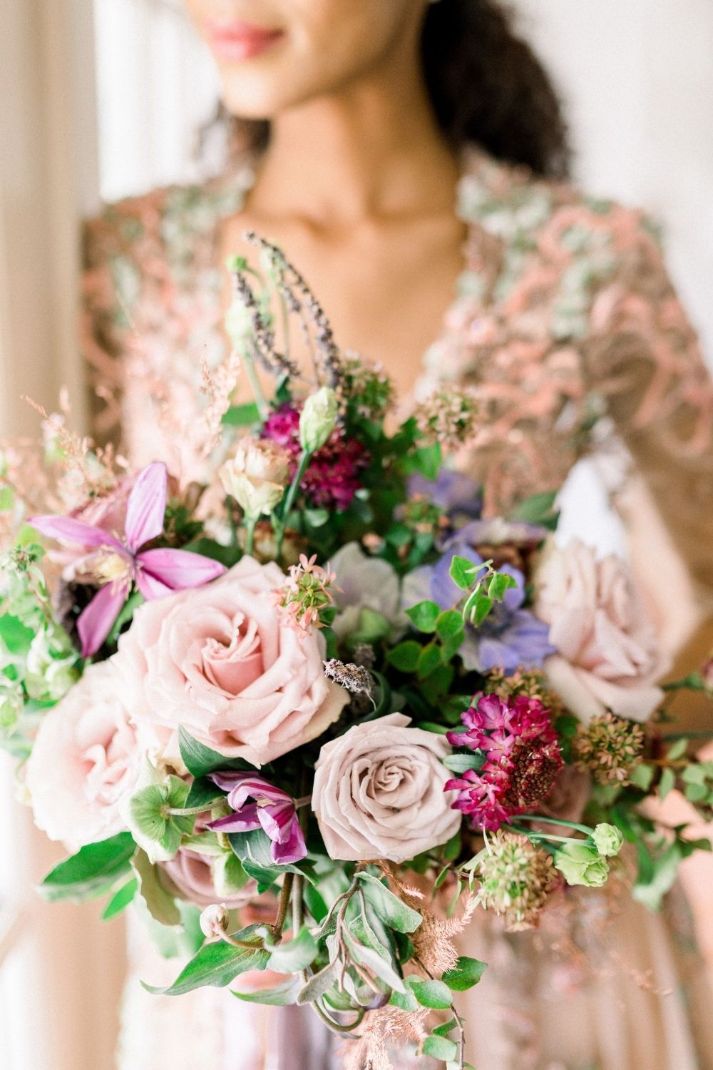 Bride in a pink blush A-line wedding dress with pink and green bouquet