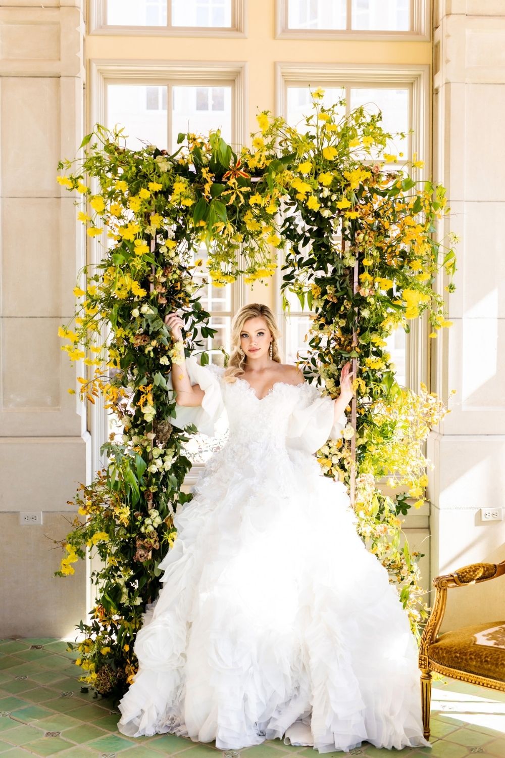 Bride in a white Ball gown wedding dress standing under yellow floral arch