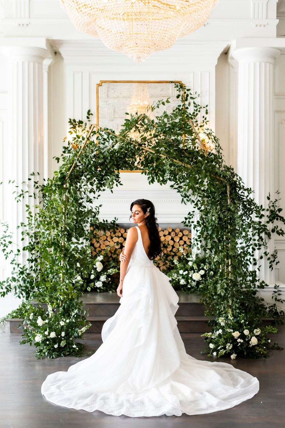 Bride in a white wedding gown with green and gold ceremony arch