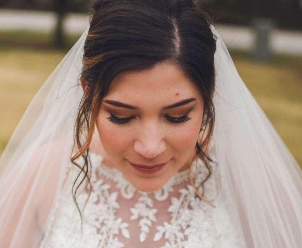Bride with white dress and veil with curls updo hairstyle in soft glam makeup